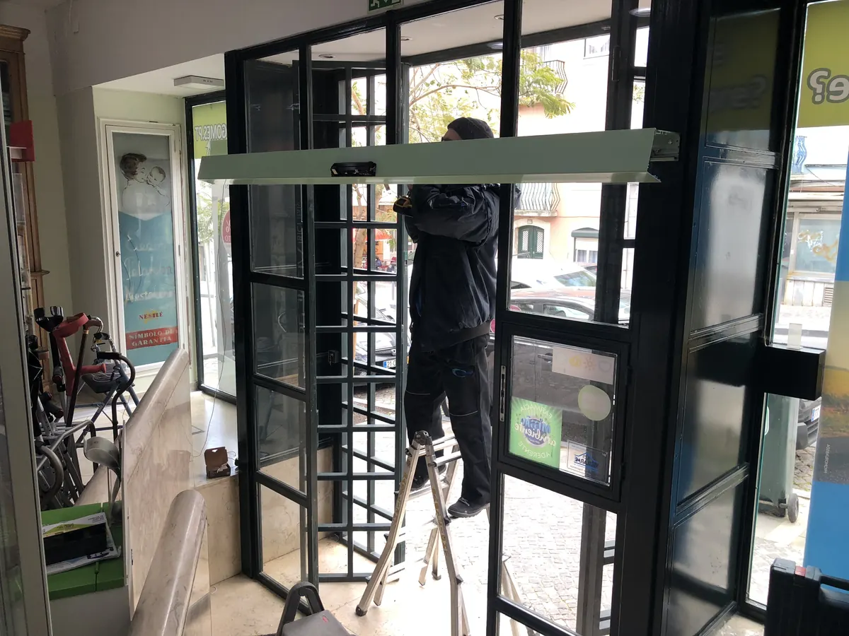 Operador automático instalado em porta clássica de ferro e vidro em loja na Ajuda, Lisboa