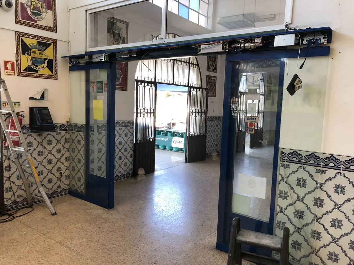 Porta automática deslizante com perfis azuis em espaço tradicional com azulejos em Pombal