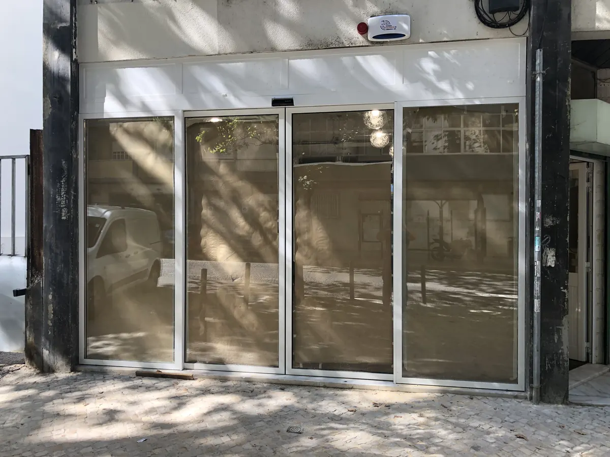 Porta automática deslizante com perfis pretos em supermercado de bairro em Benfica, Lisboa