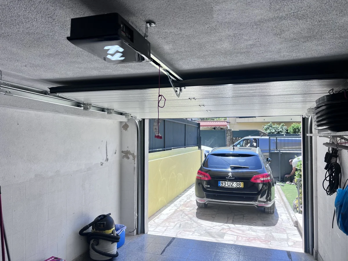 Vista interior da garagem em Mem Martins com motor de teto e portão seccional antracite aberto