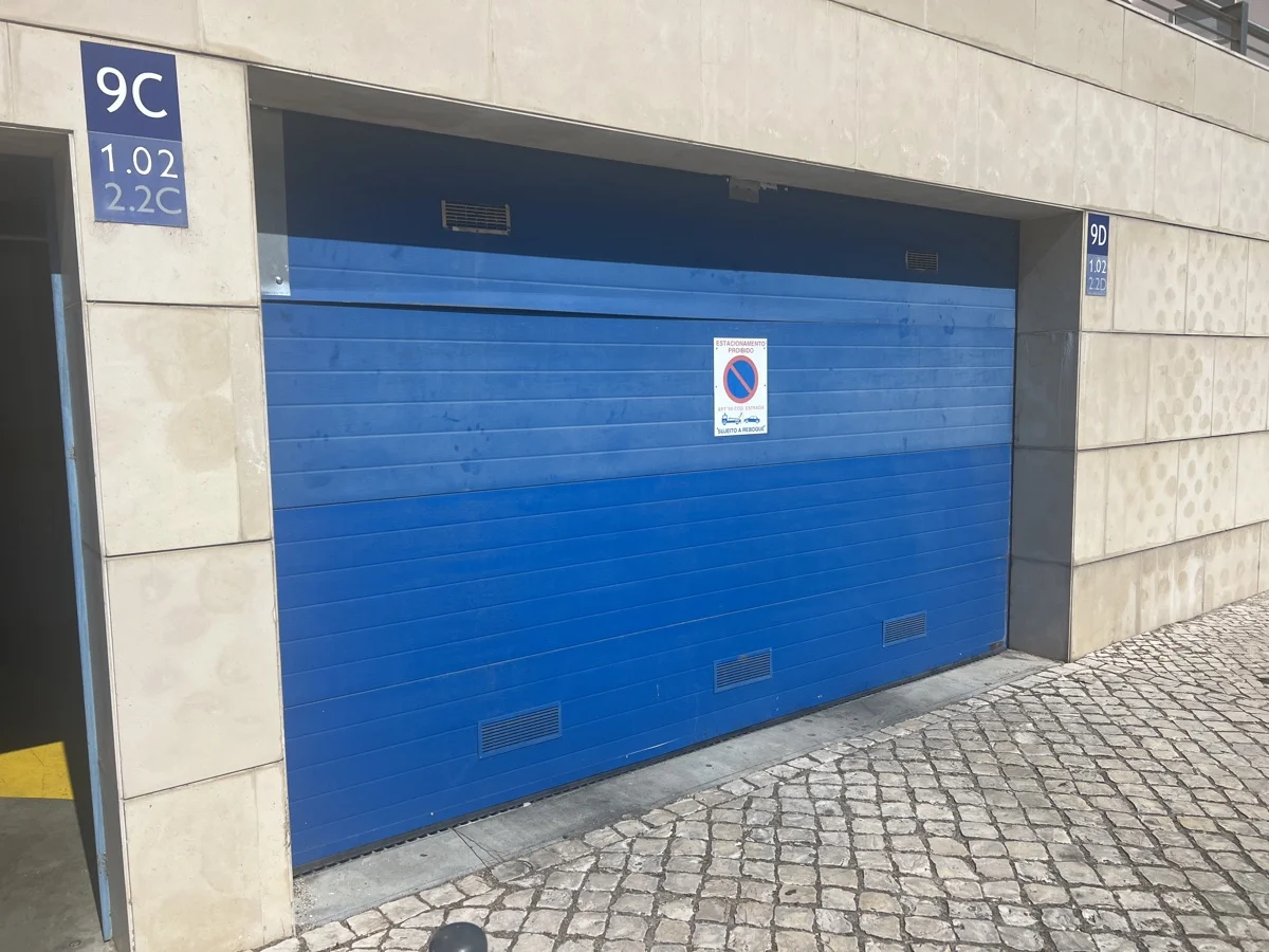 Portão seccional azul antigo antes da substituição — exterior do condomínio no Parque das Nações