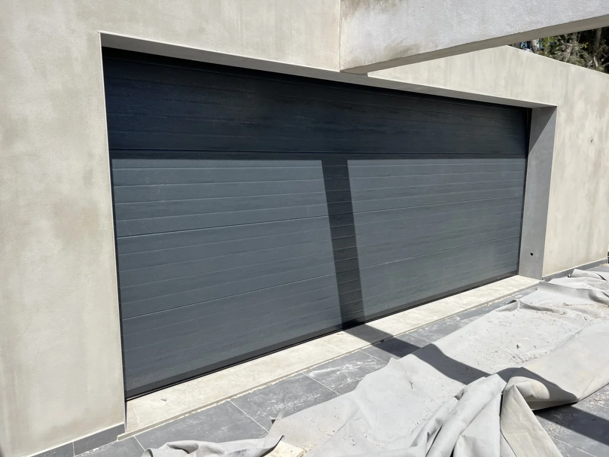 Portão de garagem seccionado cinzento escuro instalado em moradia