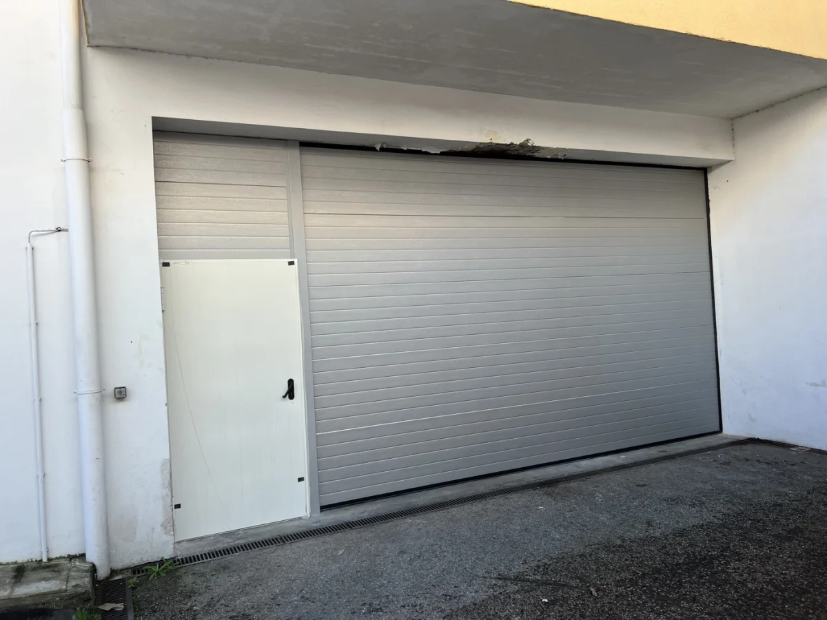 Portão de garagem seccionado branco com porta pedonal integrada